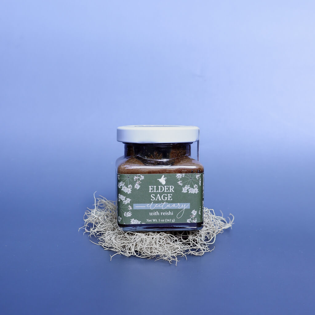 a jar of Elder Sage Herbal Honey Electuary with Reishi sitting on a decoration of dried lichen against a light blue background