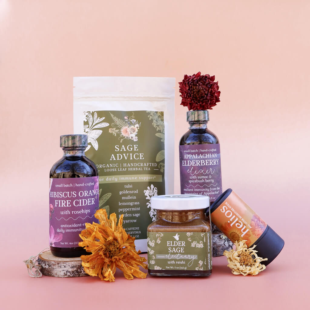 A collection of 5 Herbal products including a bag of loose-leaf herbal tea, bottles of elderberry syrup and fire cider, a jar of herbal honey, and a skin-soothing herbal salve on a pink background with dried flowers.
