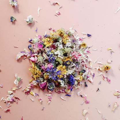 A pile of dried edible flowers against a light pink background