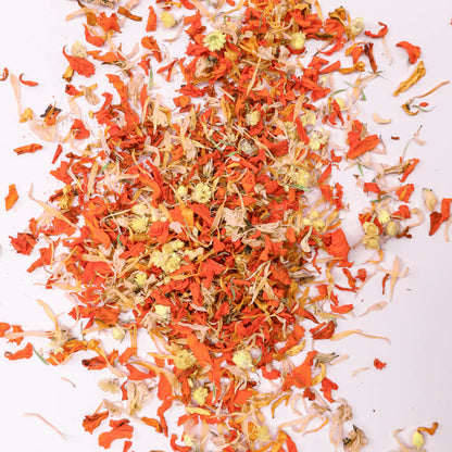 Scattered orange and yellow dried edible flowers on a white background