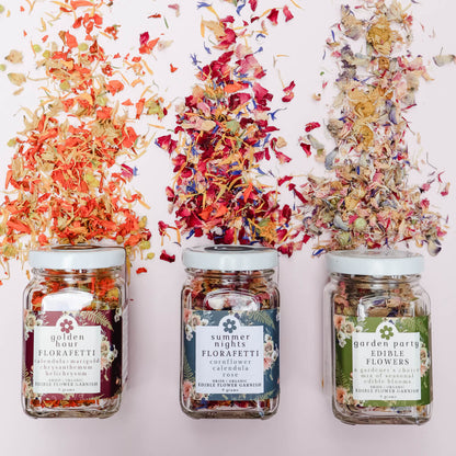 Three jars of different dried edible flower garnish blends with colorful flower confetti on a white background