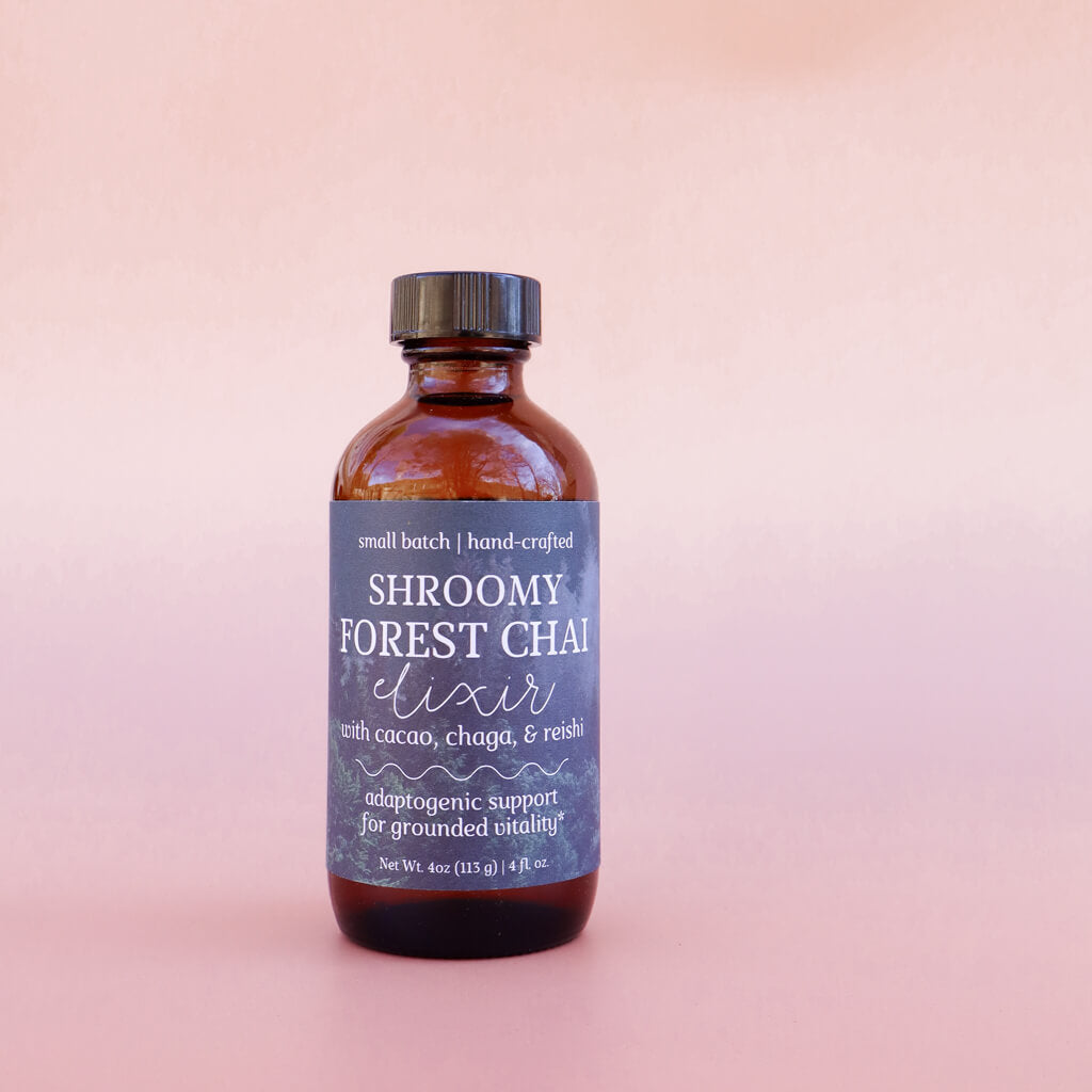 Bottle of 'Shroomy Forest Chai elixir with cacao, chaga, and reishi' on a pink background