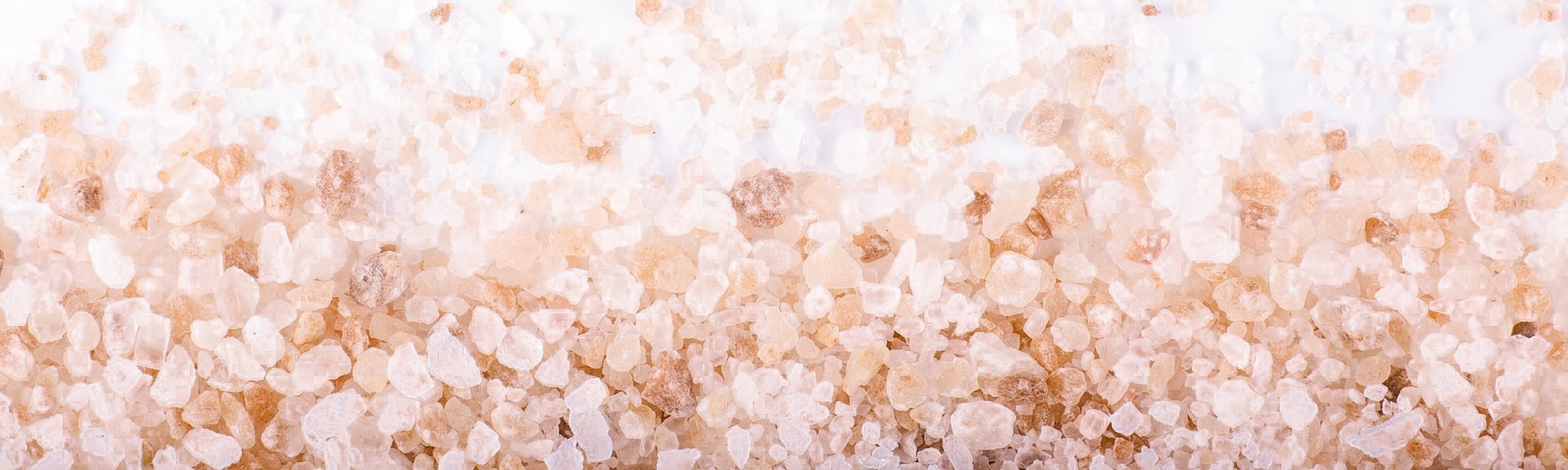 Close-up of a pile of coarse-ground mineral salt crystals on a white background