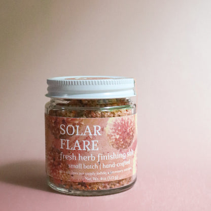 Jar of 'Solar Flare' fresh herb finishing salt on a pink background