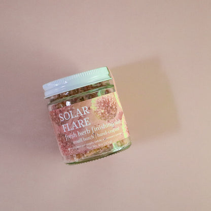 Jar of 'Solar Flare' fresh herb finishing salt on a pink background