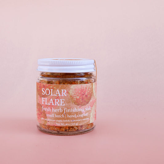 Jar of 'Solar Flare' fresh herb finishing salt on a pink background