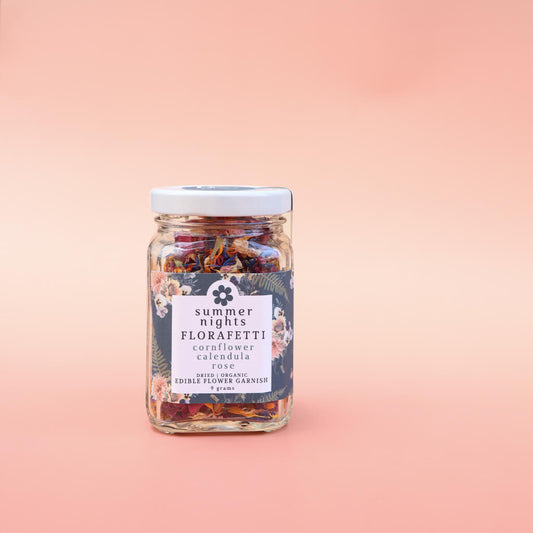 Glass jar of Summer Nights Florafetti Edible Flower Garnish on a pink background