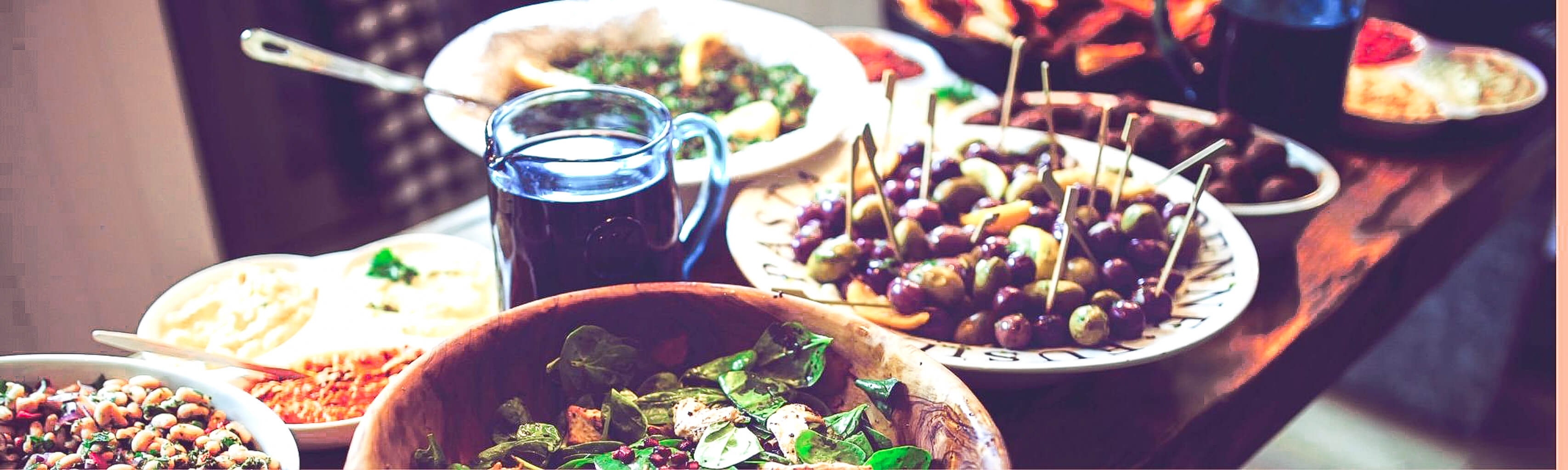 Assorted tapas on plates with a glass of red wine on a wooden table.