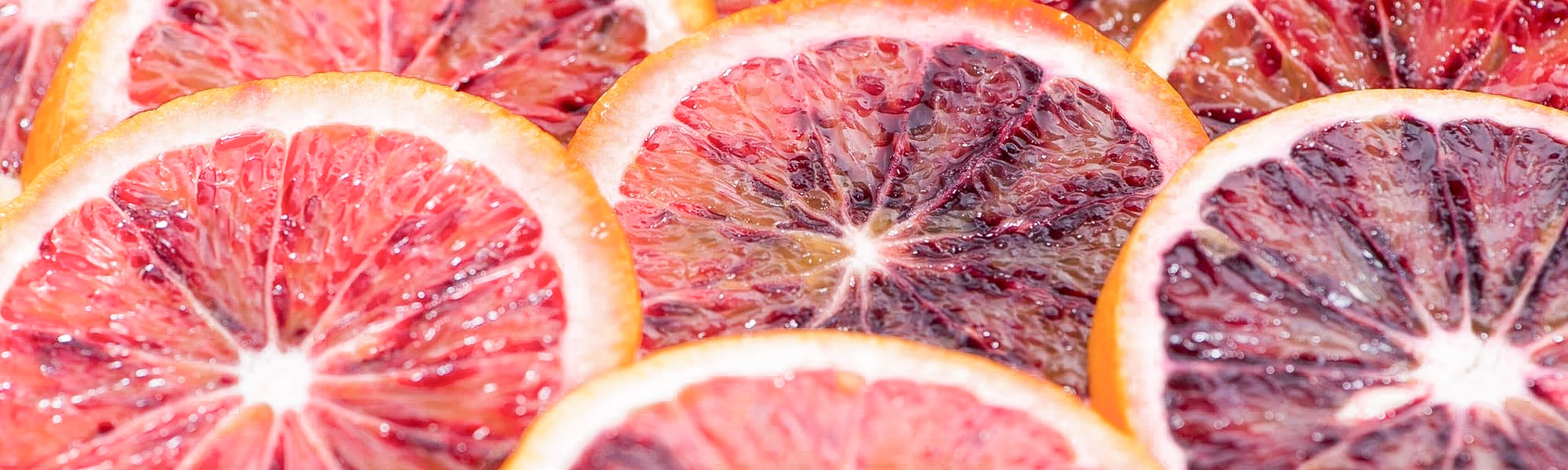 Close-up of sliced blood oranges with a vibrant pinkish-red color.