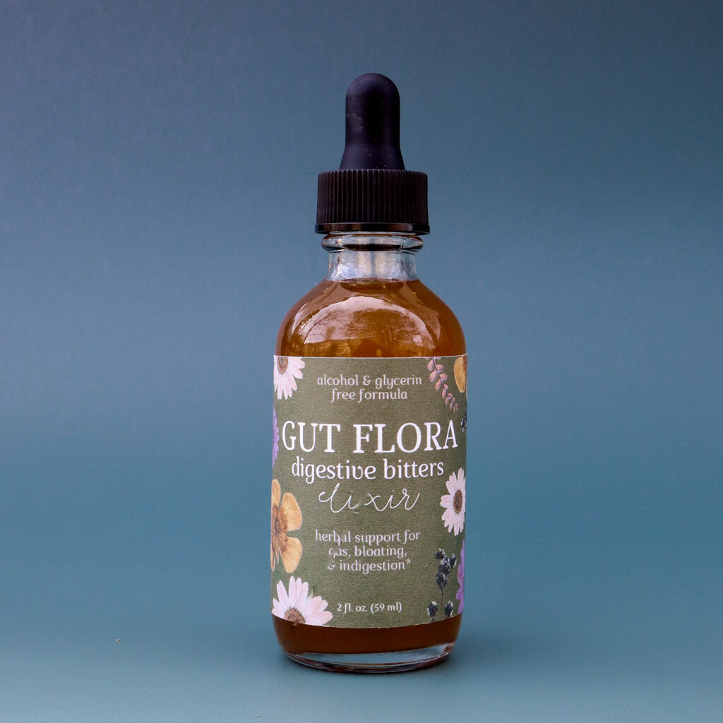Bottle of Gut Flora dandelion bitters elixir with a dropper on a blue background